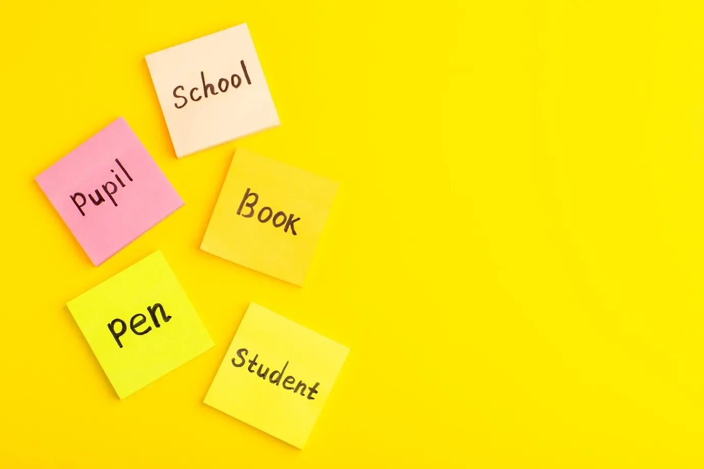 Ansicht von oben auf verschiedene Aufkleber mit Wörtern darauf, die über die gesamte gelbe Oberfläche verteilt sind.